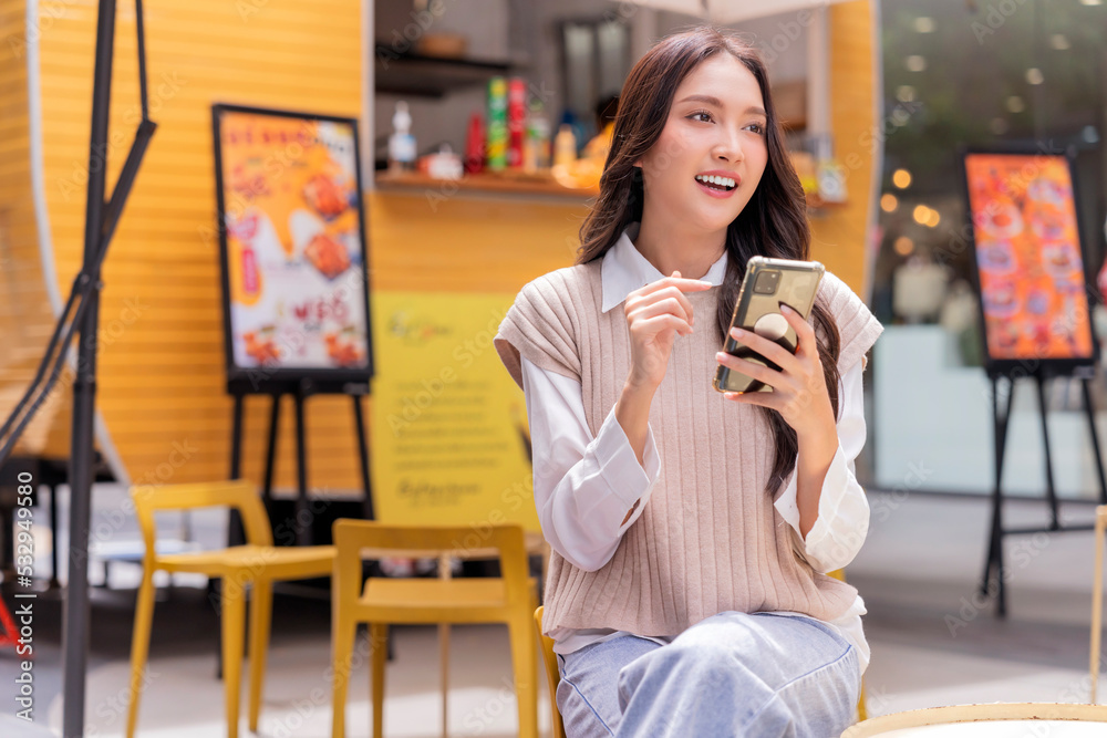 attractive asian woman pleased positive casual hand hold smartphone enjoy leisure relas sitting in f