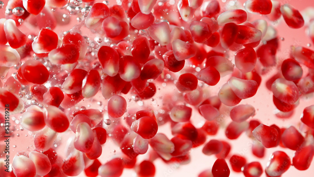 Sweet pomegranate seeds splashing underwater.