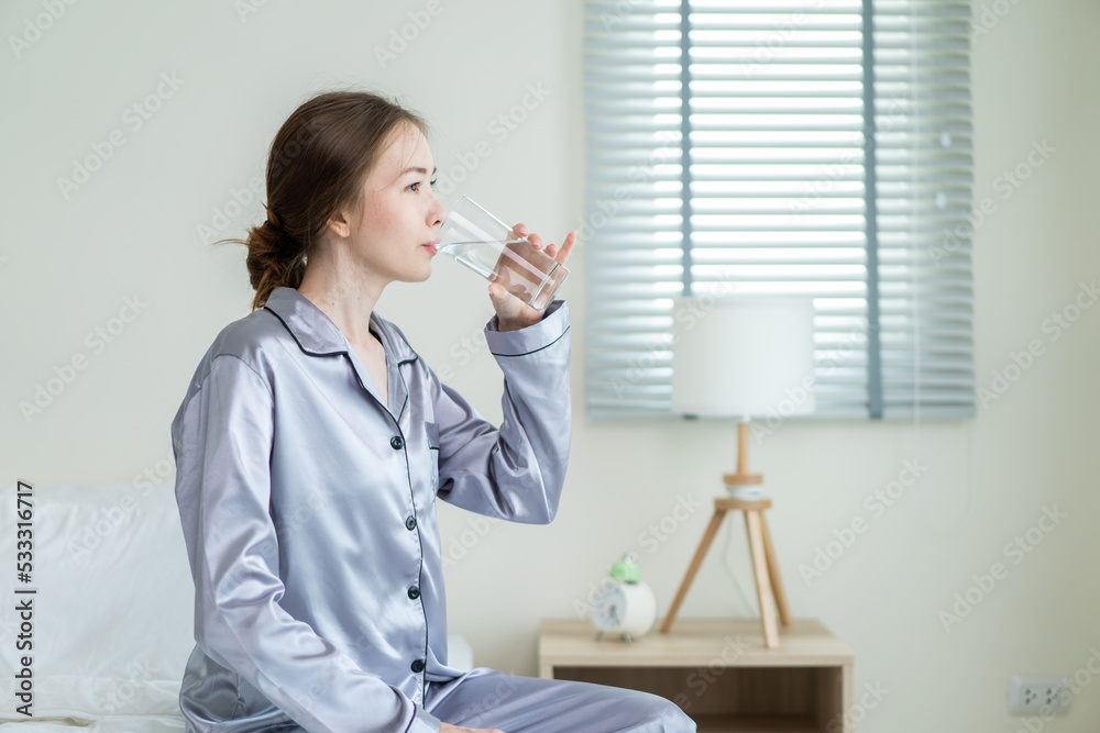 穿着睡衣的年轻高加索妇女在厨房里喝一杯水。