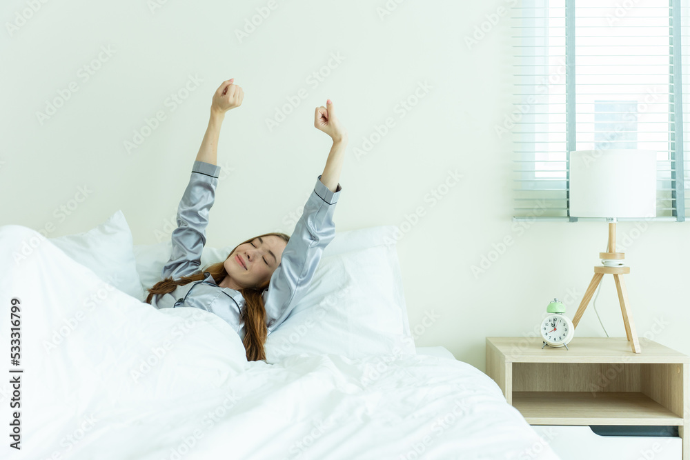 Beautiful Caucasian girl in pajamas wake up and streching in morning.