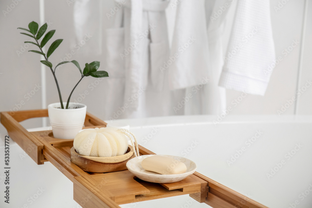 Wooden board with accessories on bathtub