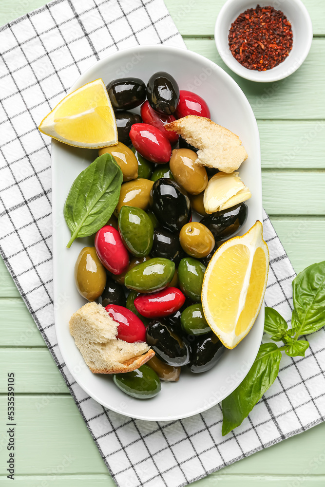 Plate with delicious olives and spices on color wooden background, closeup