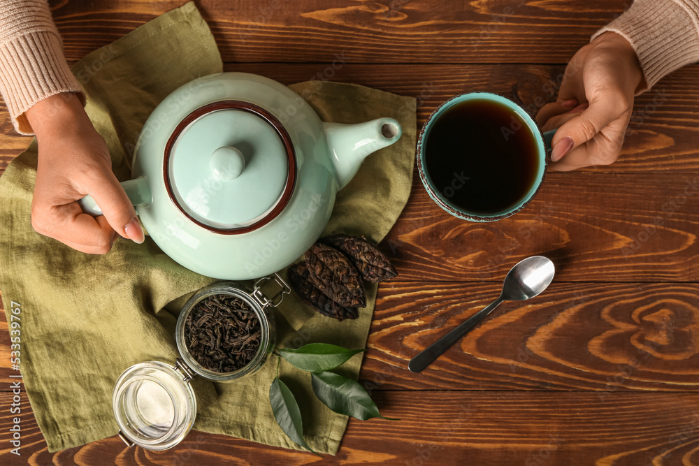 木桌上的女人端着一杯芳香的普洱茶