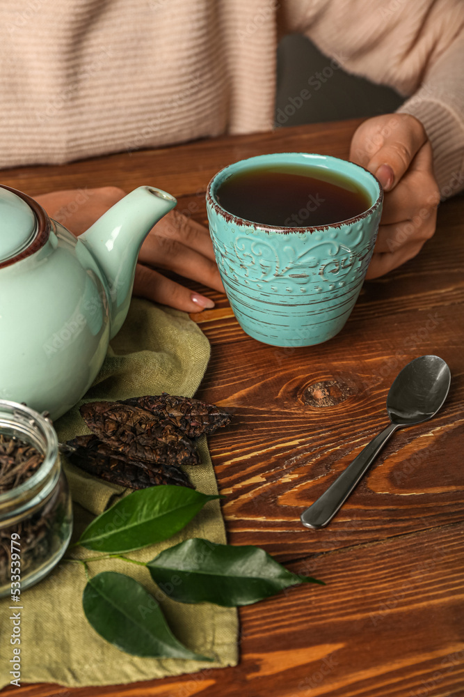 木桌上的女人端着一杯芳香的普洱茶