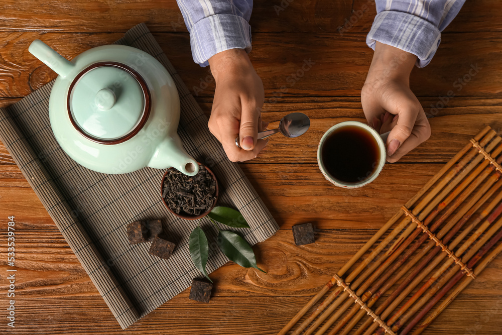 女性手拿一杯普洱茶和木底干压叶