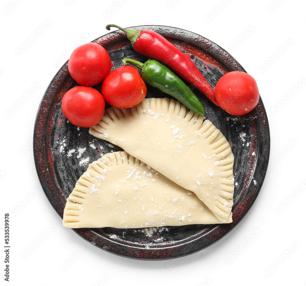 Plate with raw chebureks, tomatoes and chili peppers on white background