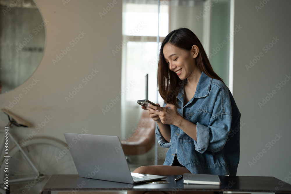 一位年轻的亚洲女性在咖啡店打电话，面带微笑。