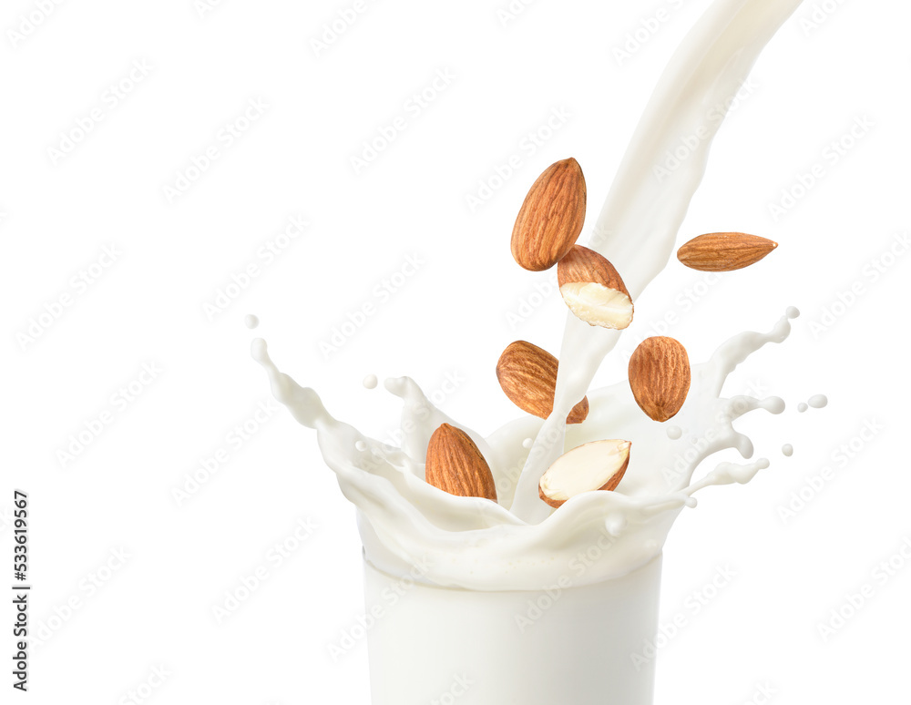 Pouring almond milk with splashing and almond nuts isolated on white baclground.