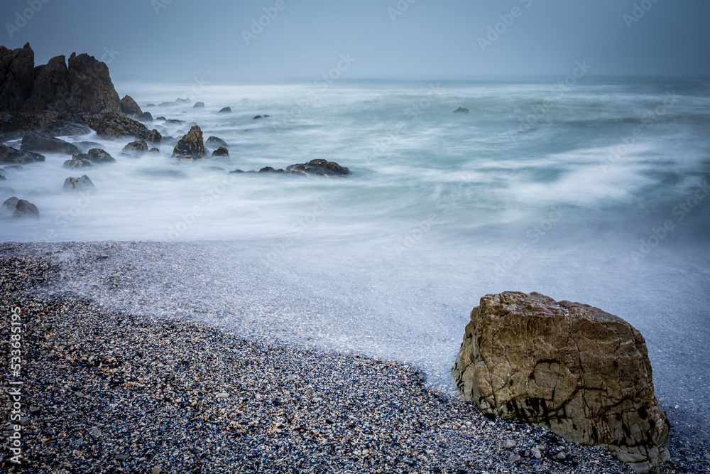 Moody Skulpiesbaai seascape under a brooding sky, the water and waves blurred because of long exposu