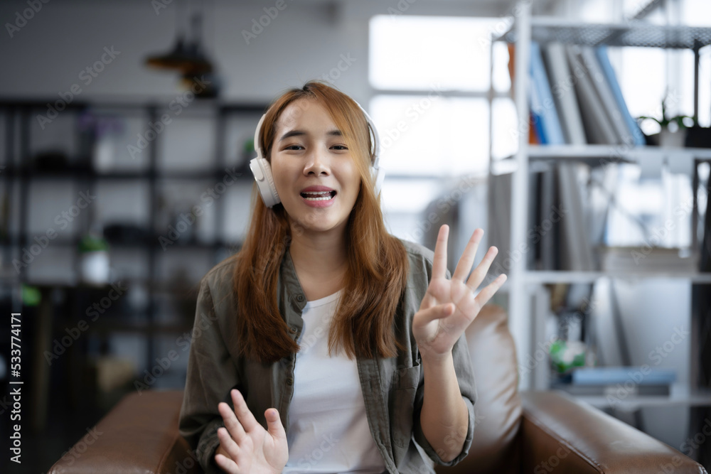 年轻的亚洲女性使用笔记本电脑在线会议在客厅的视频电话会议中交谈