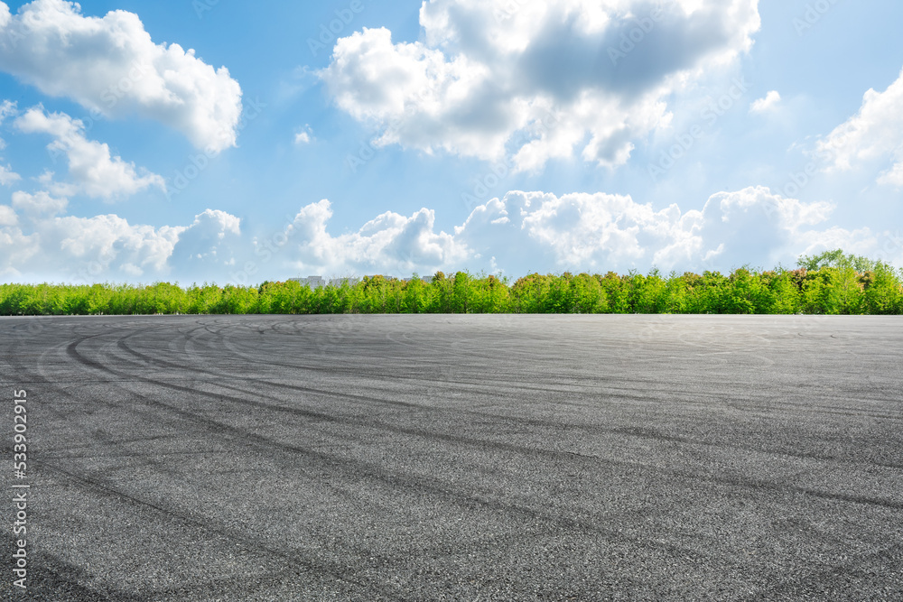 Empty asphalt road and green forest with sky clouds background