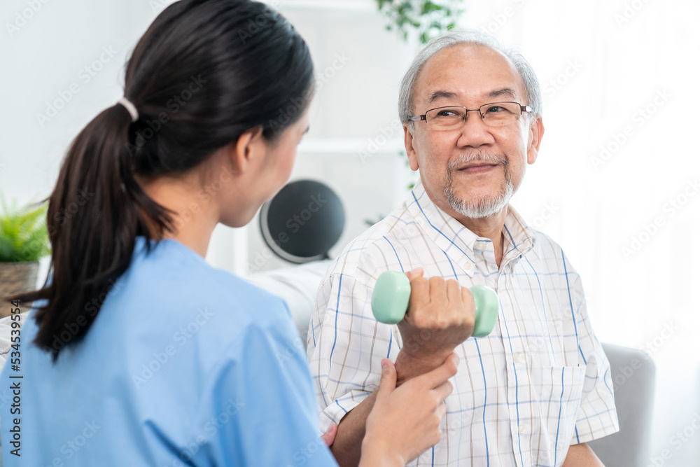 Contented senior patient doing physical therapy with the help of his caregiver. Senior physical ther