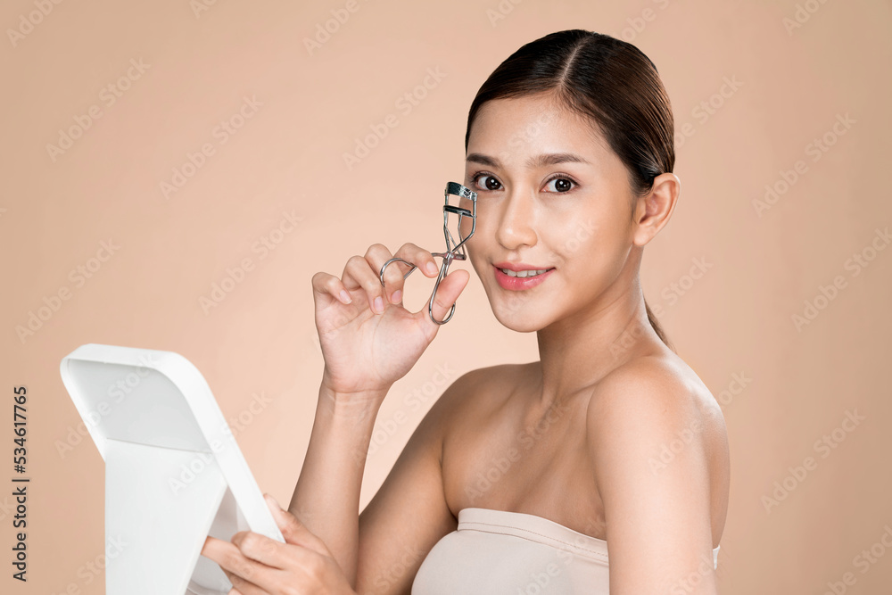 Young ardent woman model with healthy flawless fair skin and soft makeup looking at camera while usi