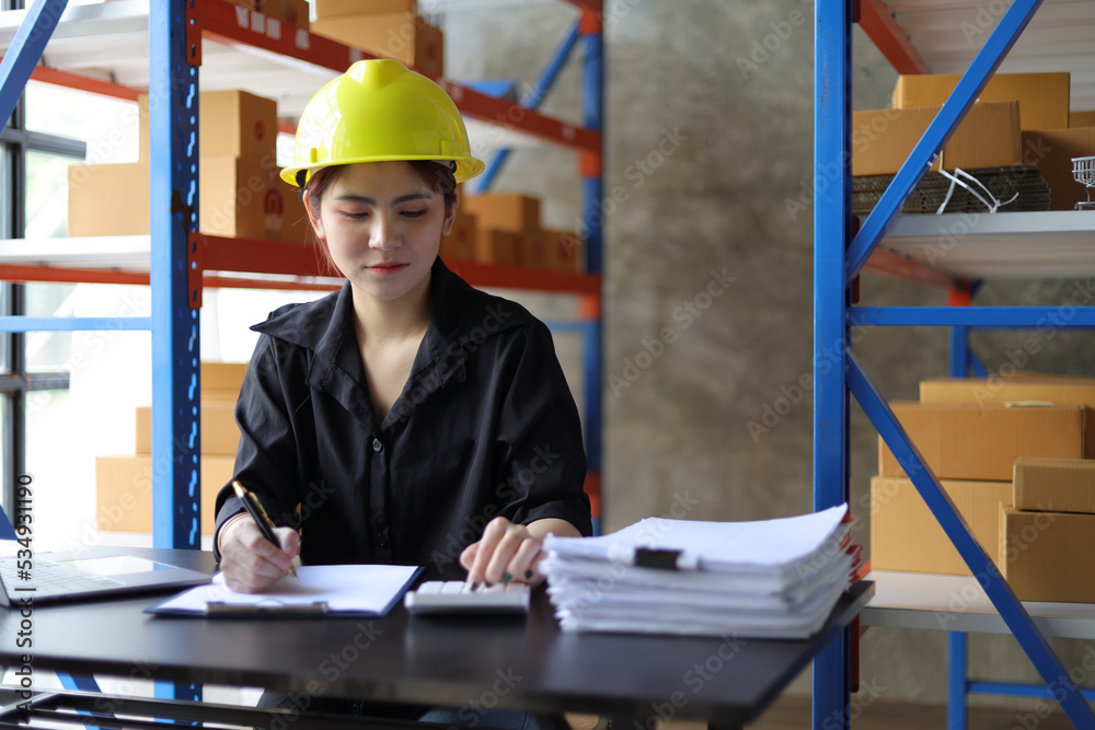 Small warehouse worker working with a laptop is checking the inventory. Entrepreneurs start-up e-com