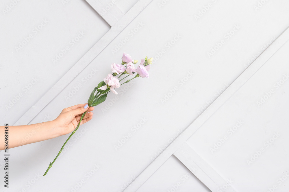 Female hand with beautiful manicure and blooming flowers on light background