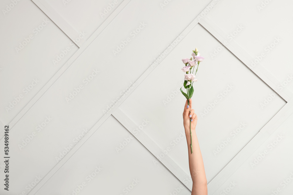 Female hand with beautiful manicure and branch of blooming flowers on light background