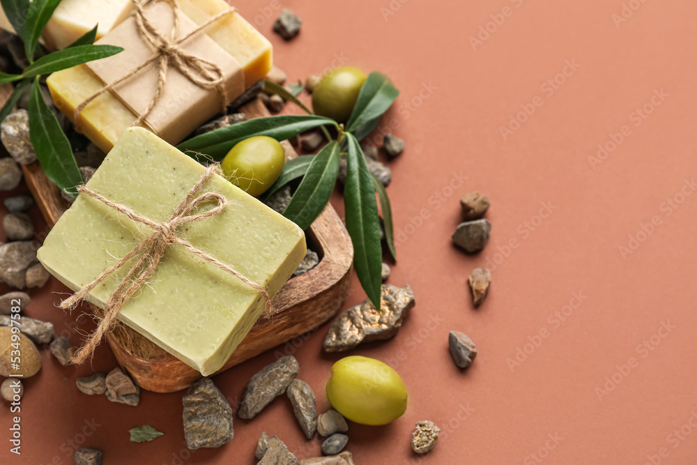 Board with olive soap bars and stones on color background, closeup