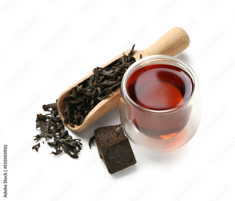 Scoop of dry puer tea and glass on white background