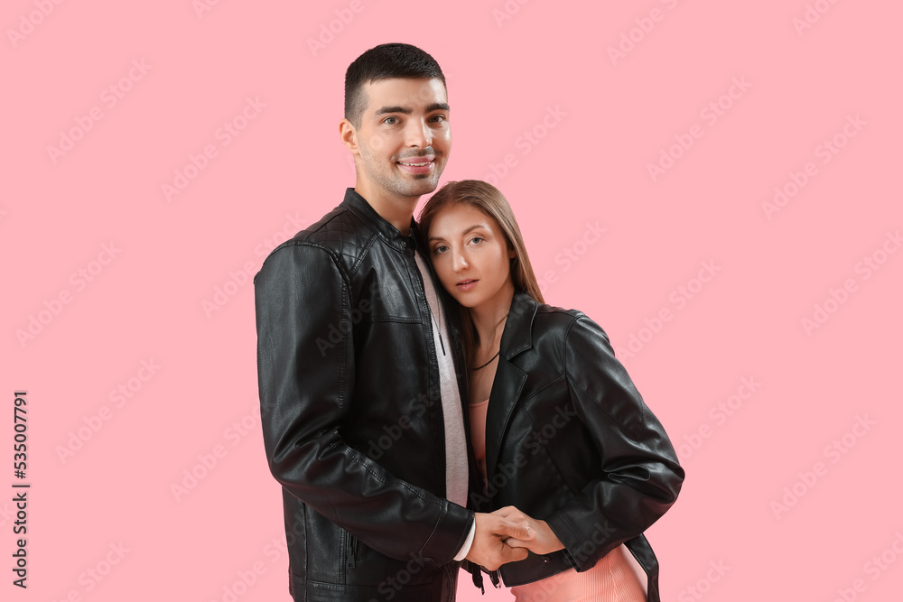 Fashionable young couple in autumn clothes on pink background