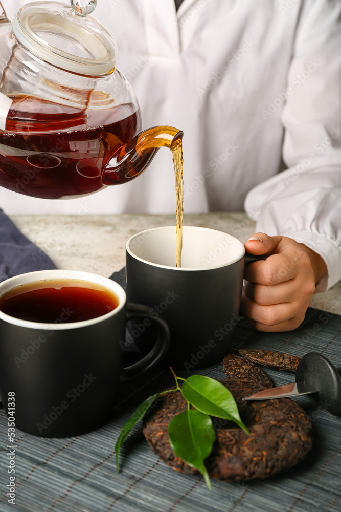 Woman pouring tasty puer tea at table, closeup