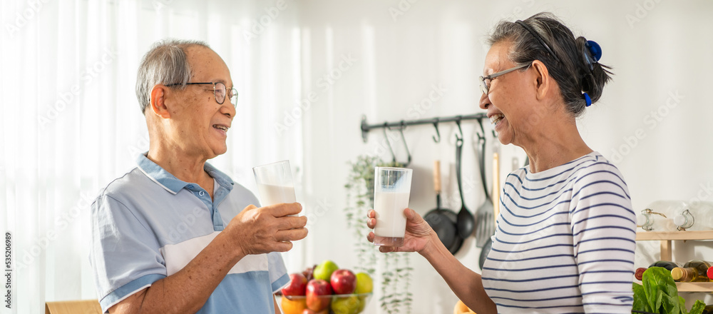 亚洲一对老年夫妇在家里的厨房里喝了一杯牛奶。