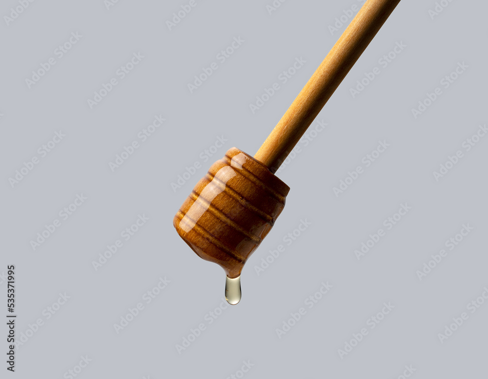 Honey and wooden honey dipper on gray background.