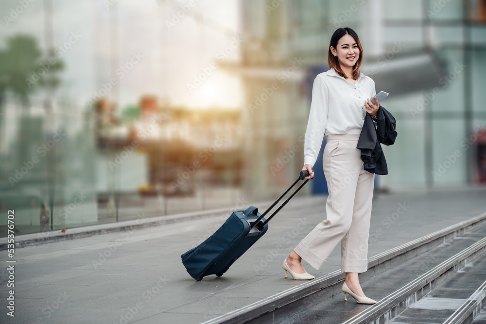 Young Asian businesswoman talking on phone and walking in airport before business trip. Beautiful wo