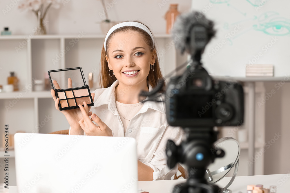 Young beauty blogger with eyeshadows and brush recording video in dressing room