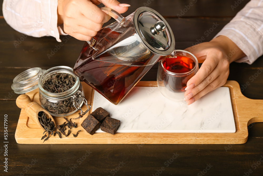 Woman pouring tasty puer tea at table