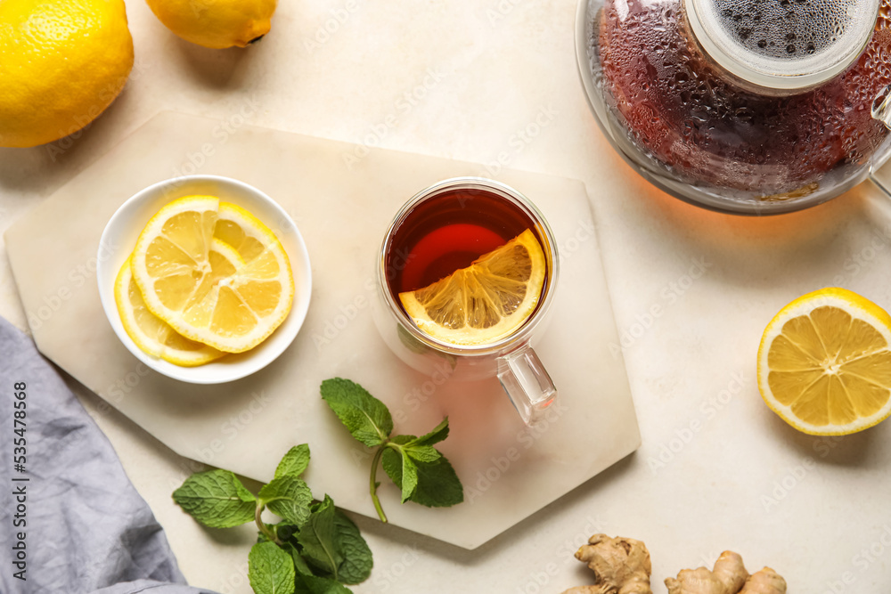 Board with glass cup of black tea, lemon and mint on white background