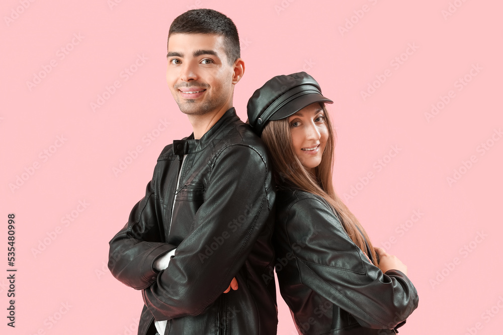 Fashionable young couple in autumn clothes on pink background