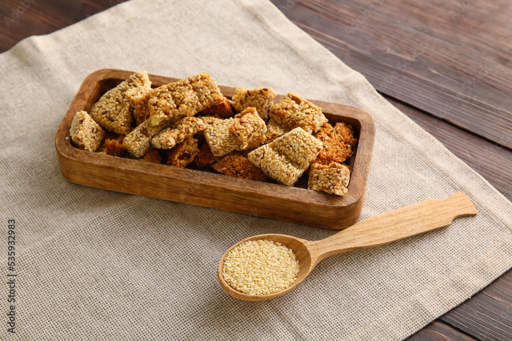 Board of tasty kozinaki with sesame seeds on dark wooden background