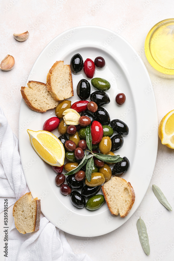 Plate with different kinds of tasty olives and bread on light background, closeup