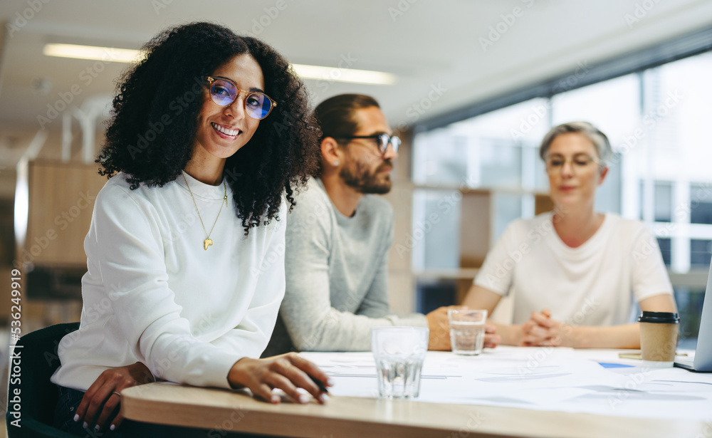 Cheerful young businesswoman attending a meeting with her team