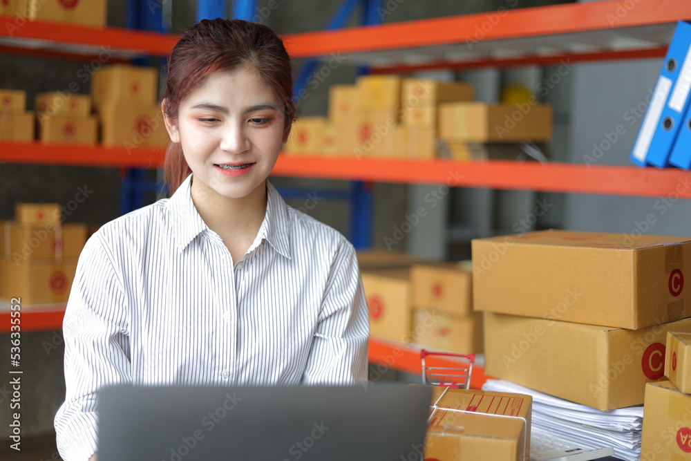 Small warehouse worker working with a laptop is checking the inventory. Entrepreneurs start-up e-com