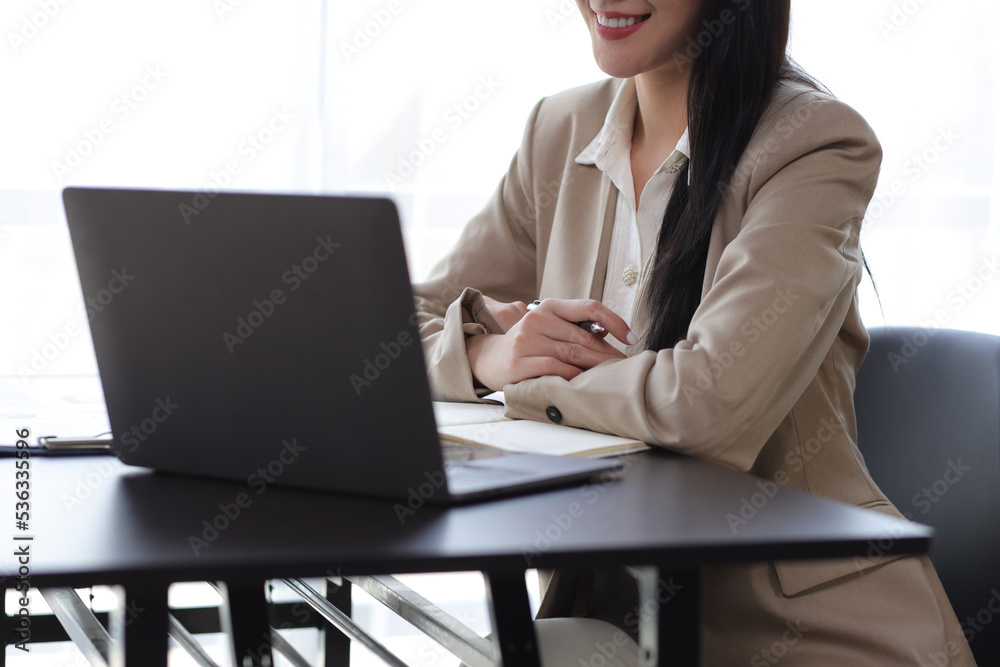 Attractive beautiful Asian business woman working on laptop on desk in office.