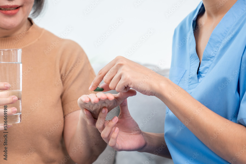 Contented senior woman taking medicines while her caregiver advising her medication. Medication for 