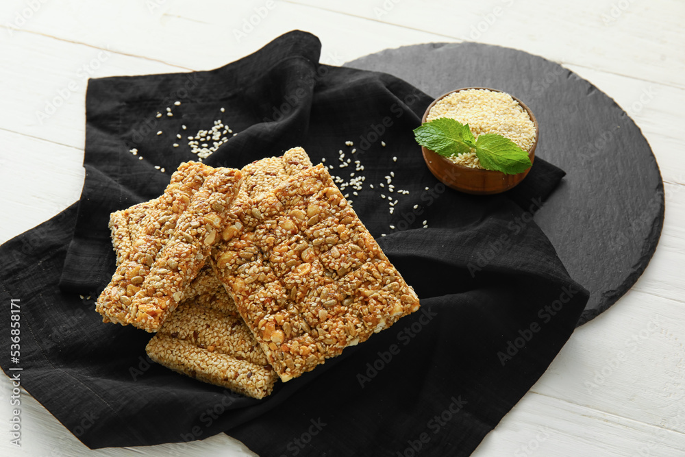 Tasty kozinaki bars with sesame seeds on light wooden background