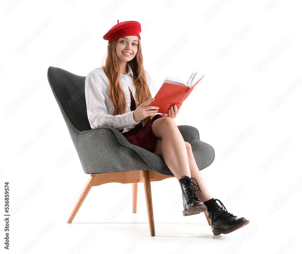 Stylish young woman with book sitting in armchair on white background