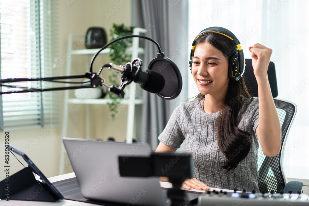 一位亚洲有魅力的音频DJ女士对着麦克风对着广播讲话。