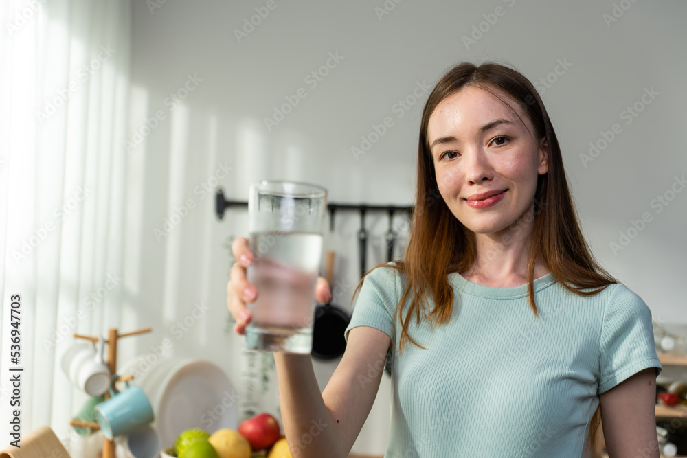 高加索妇女在家里的厨房里喝一杯水的肖像。