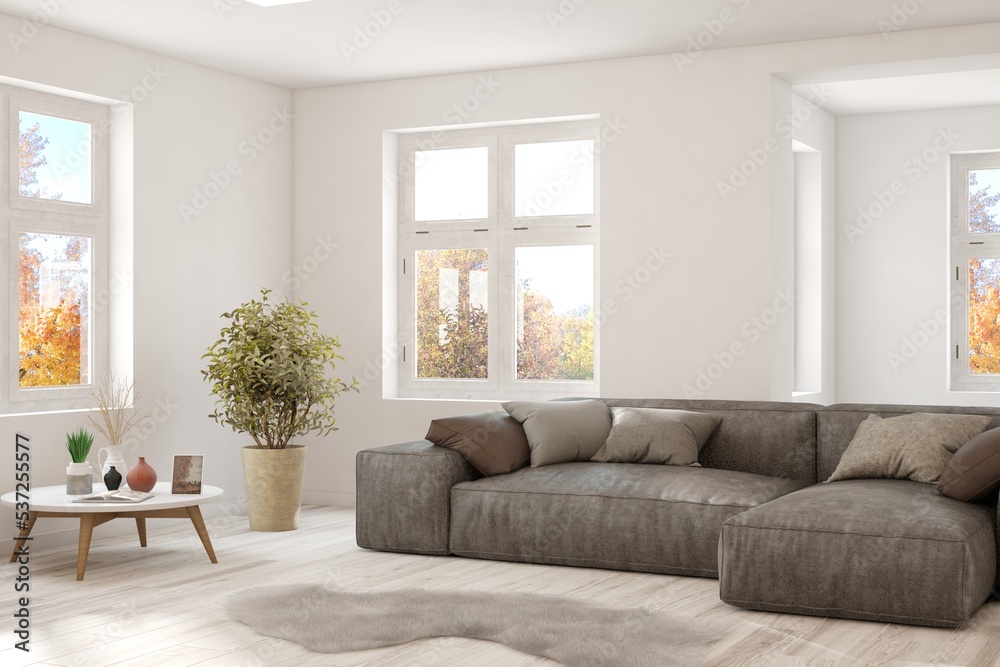 Stylish room in white color with sofa and autumn landscape in window. Scandinavian interior design. 