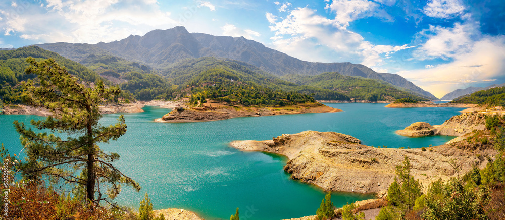 Beautiful panorama of nature of a mountain valley with a lone cedar, a large lake with water sparkli