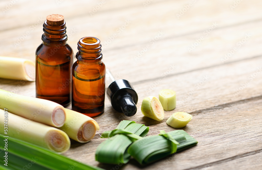 Lemongrass essential oil extract with fresh lemongrass on wooden table.