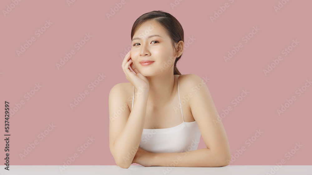 Close up portrait beauty shot of Beautiful Asian girl looking at camera isolated on pink background 