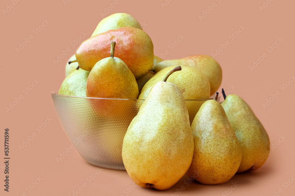 Glass bowl of tasty ripe pears on color background