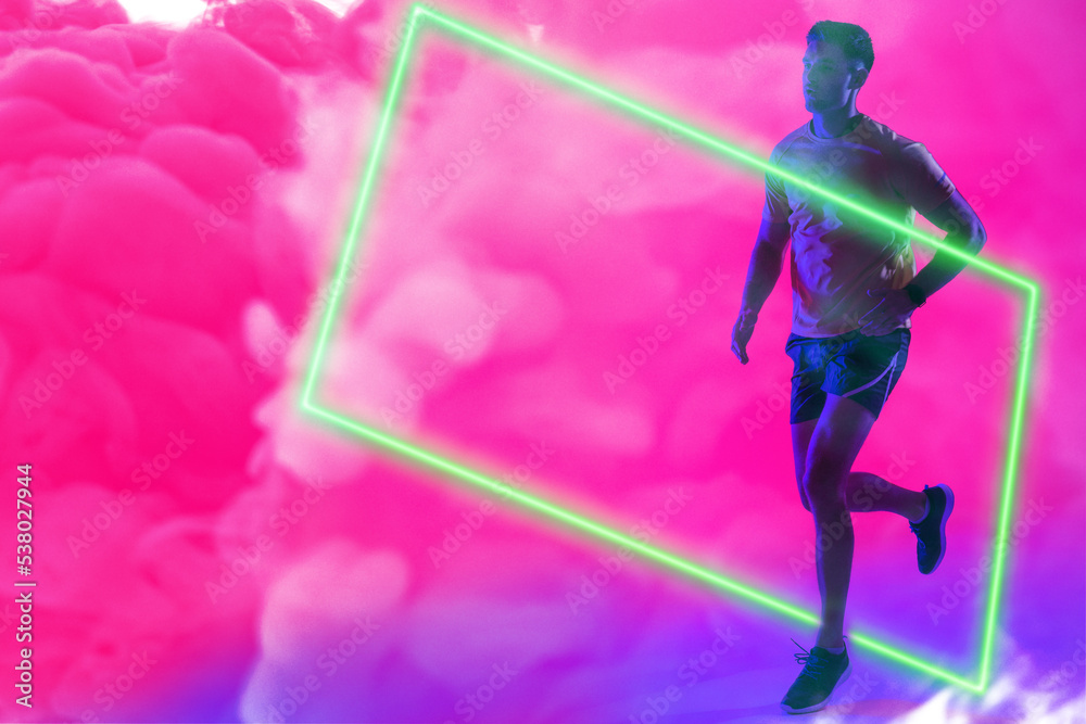 Full length of caucasian sportsman running over illuminated rectangle against pink smoky background