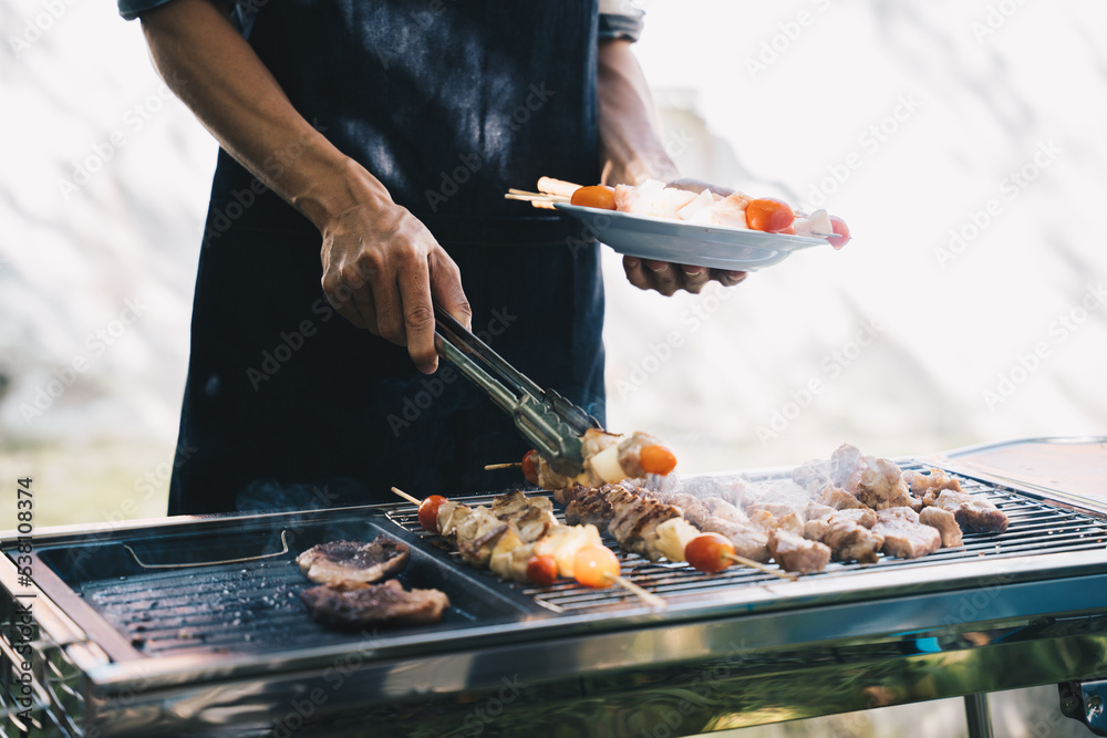 一个男人在朋友聚会上拿着烧烤盘。食物、人和家庭时间概念。