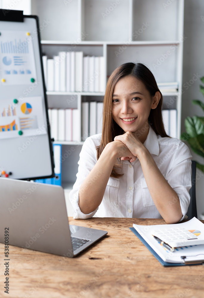 一位亚洲年轻企业的画像女性在工作站上的笔记本电脑上工作。商业