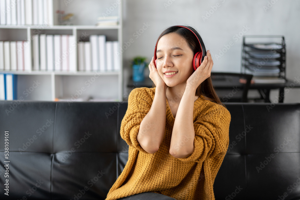 一位快乐的年轻亚洲女性在音乐应用程序中用无线耳机听音乐的肖像